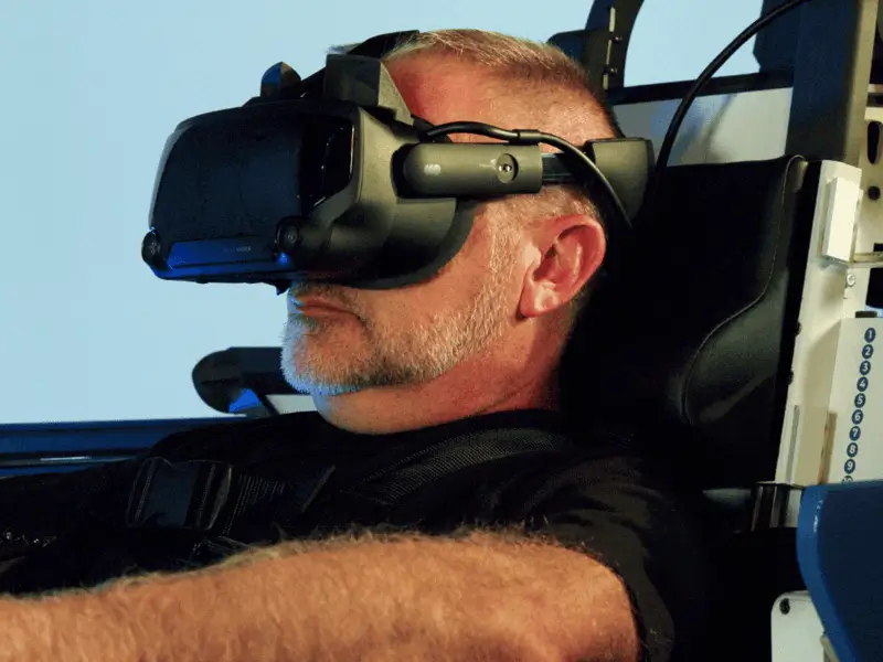 A photo of a man wearing a VR headset sitting inside the machine